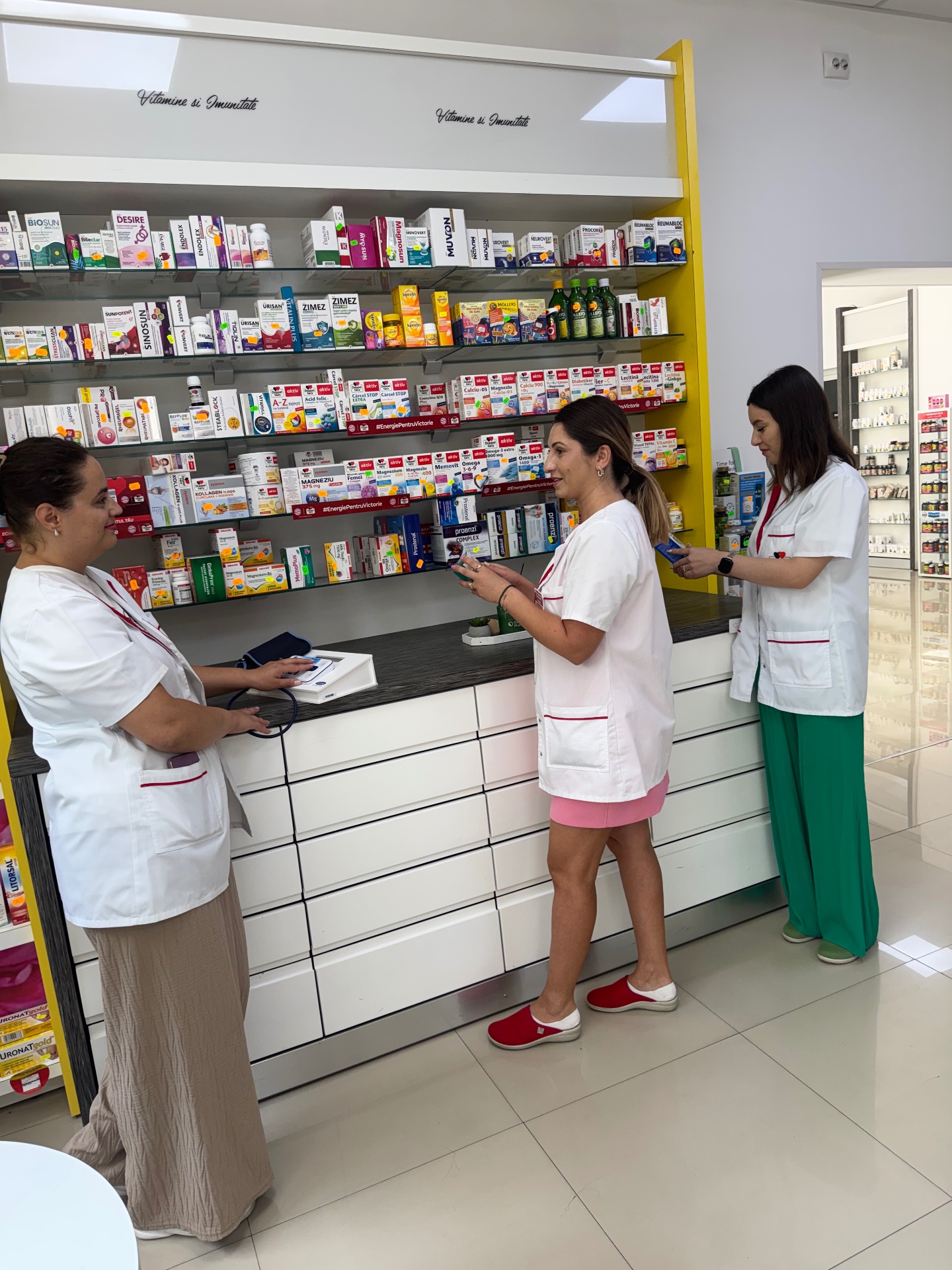 Farmaciste lângă raftul de vitamine și imunitate din farmacie
